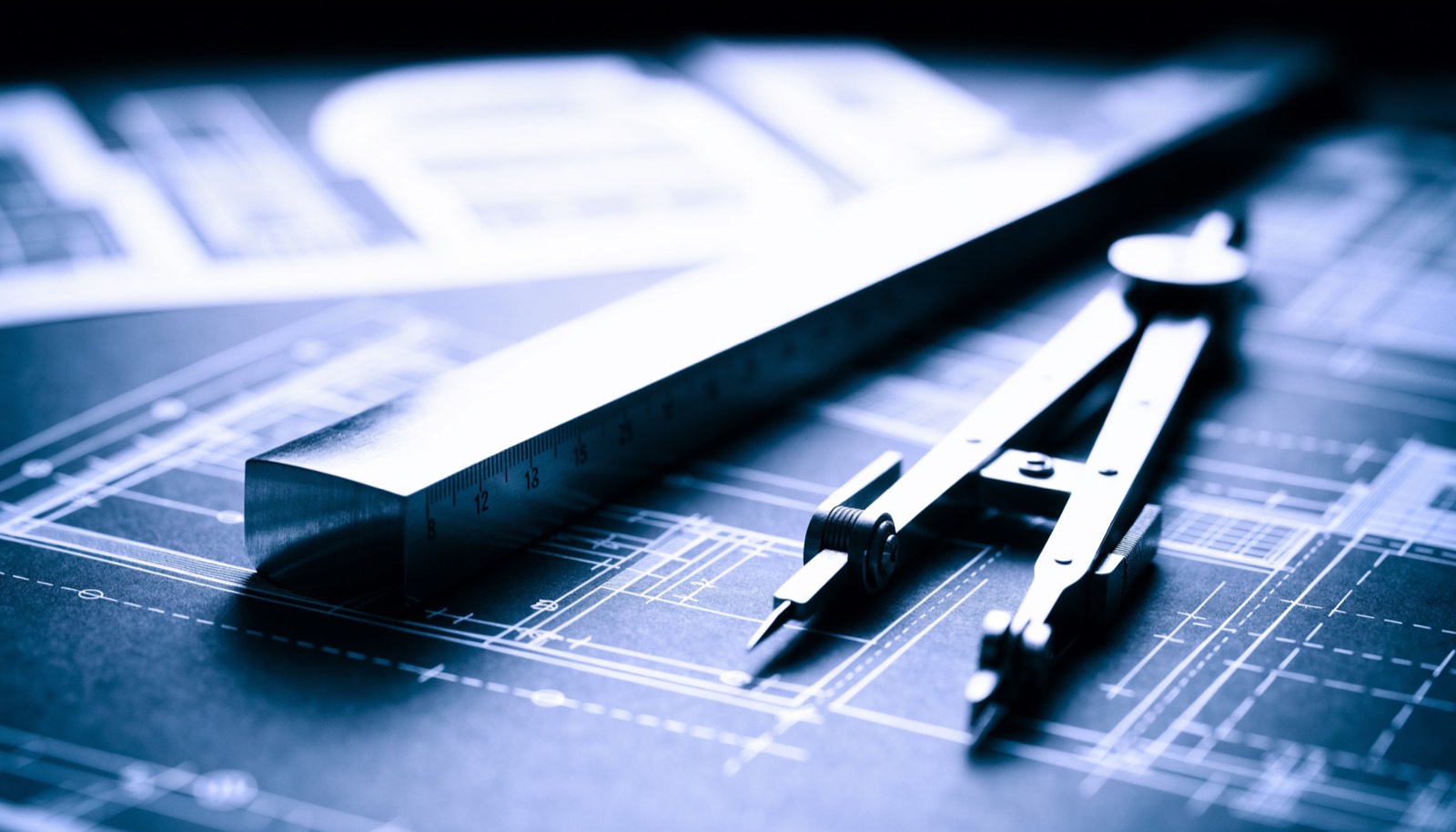 Close view of blueprint sheets and drafting tools, in dark blueprint tones
