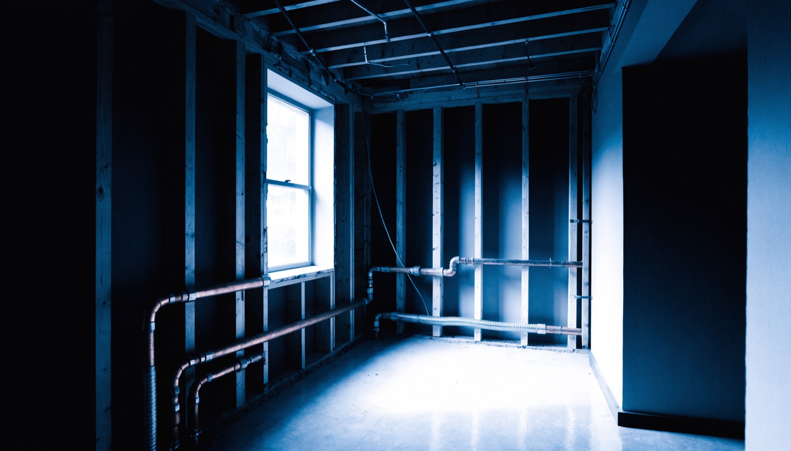 A kitchen gutted to the studs during a remodel, in dark blueprint tones